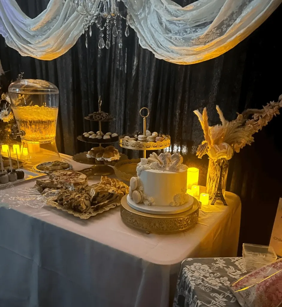 Birthday in Paris dessert table with glowing drink dispenser, gold stands, cake, and candlelight