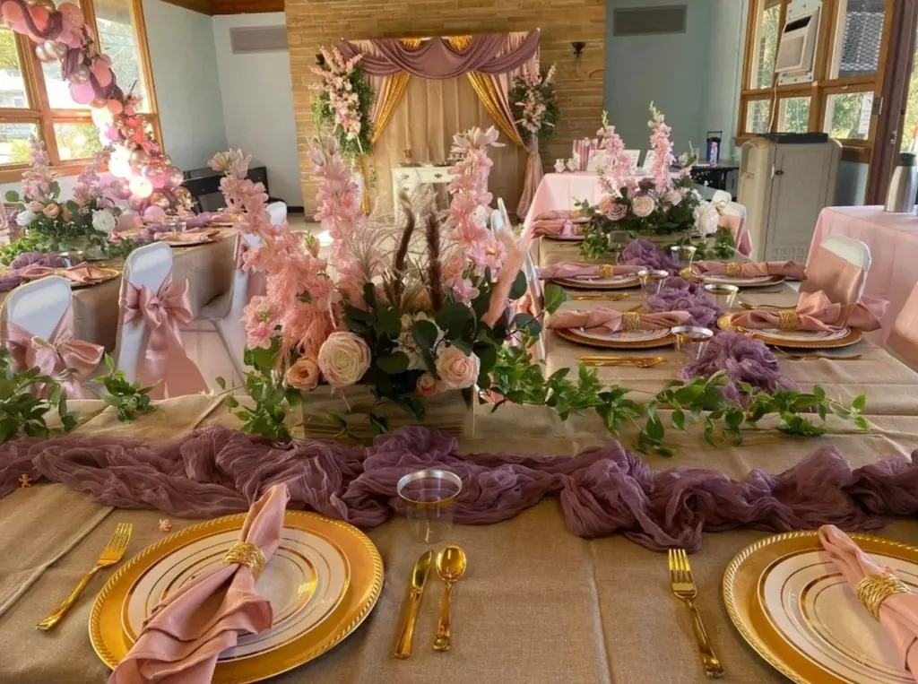 Boho baby shower long tables with gold chargers, blush bows, and soft florals