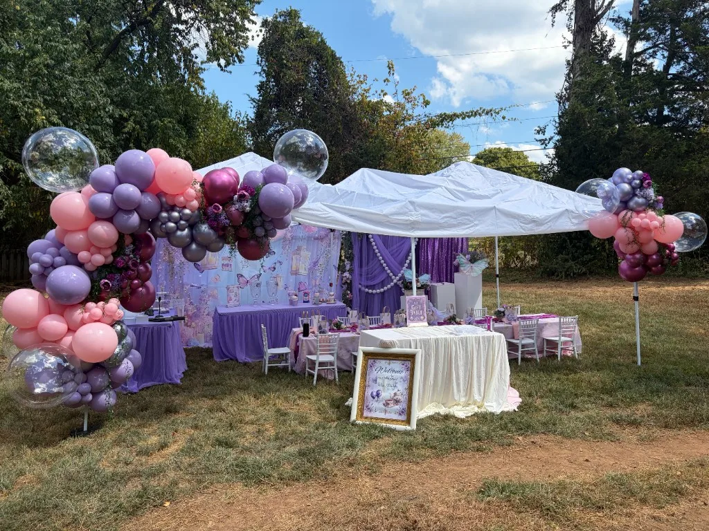 Outdoor tented purple butterfly tea party with balloon garlands and children's dining table