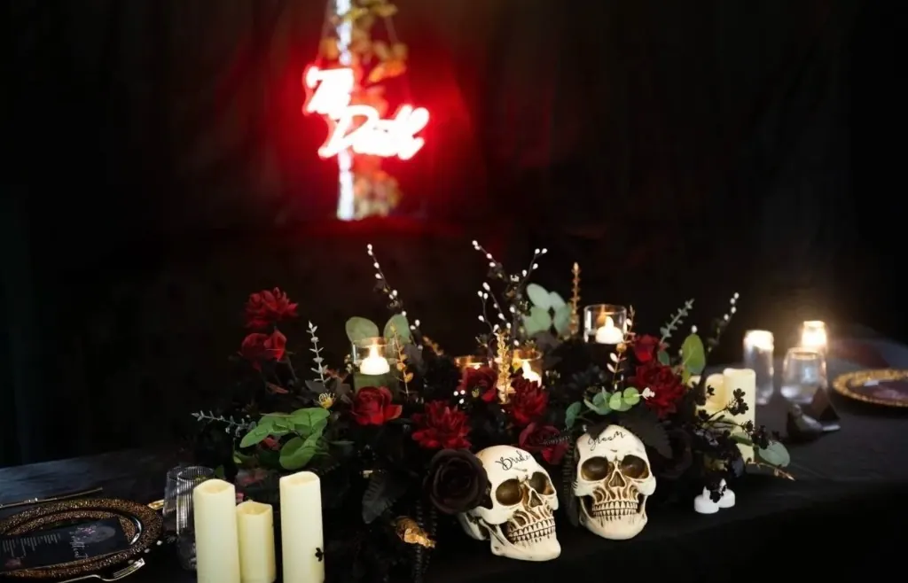 Gothic backyard wedding tablescape with deep red florals, Bride and Groom skulls, and candlelight