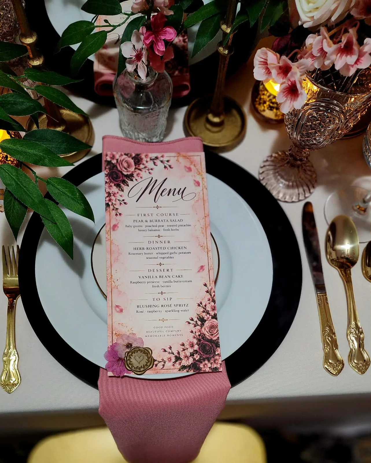 Overhead place setting with black charger, custom floral menu, wax seal, and gold flatware