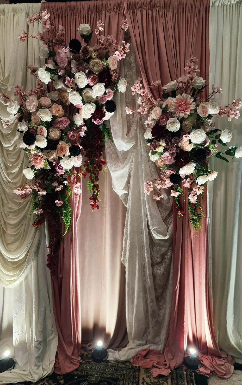 Ivory, blush, and lace draping with cascading floral installations and uplighting