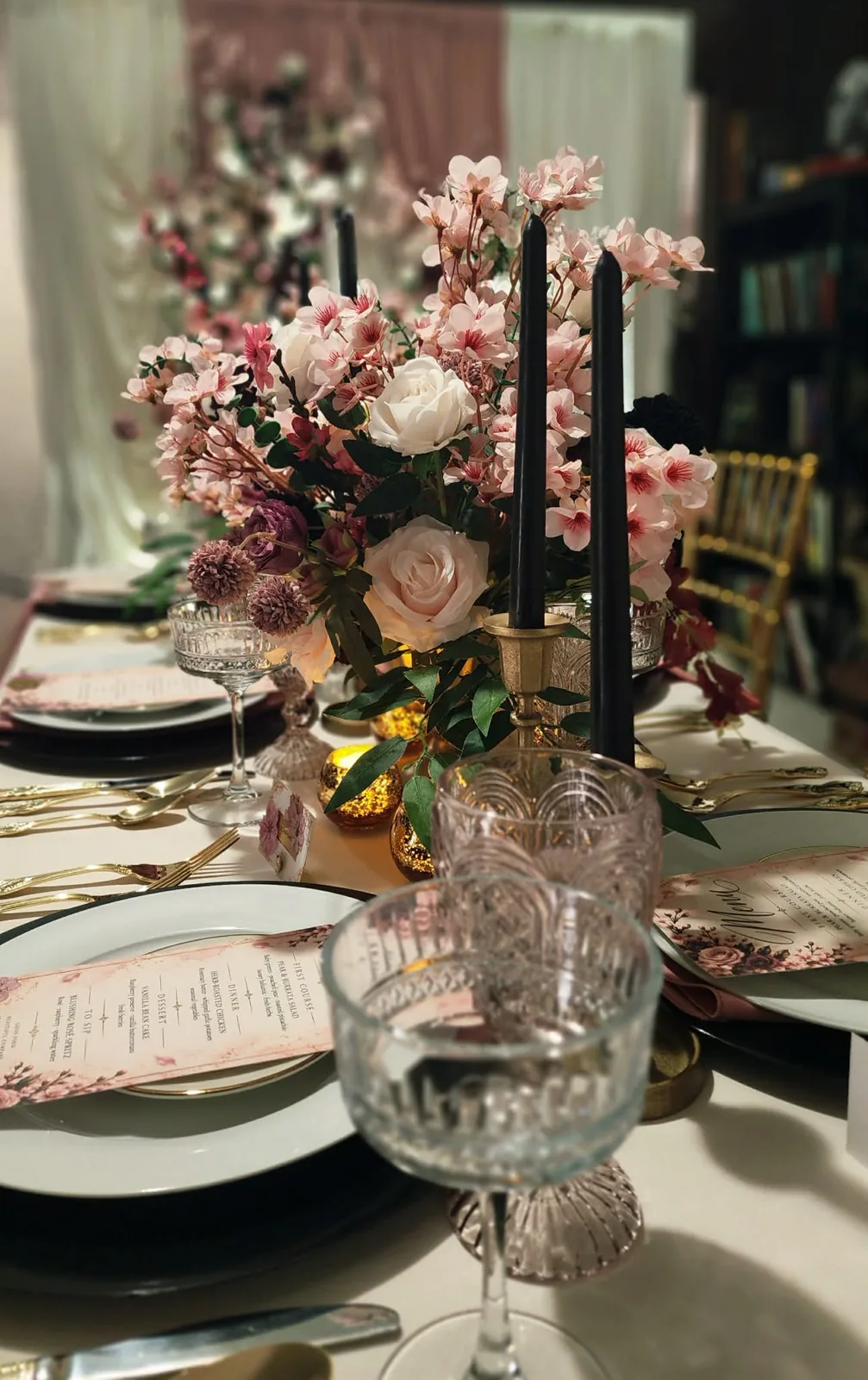 Intimate table detail with black taper candles, roses, and pink vintage glassware