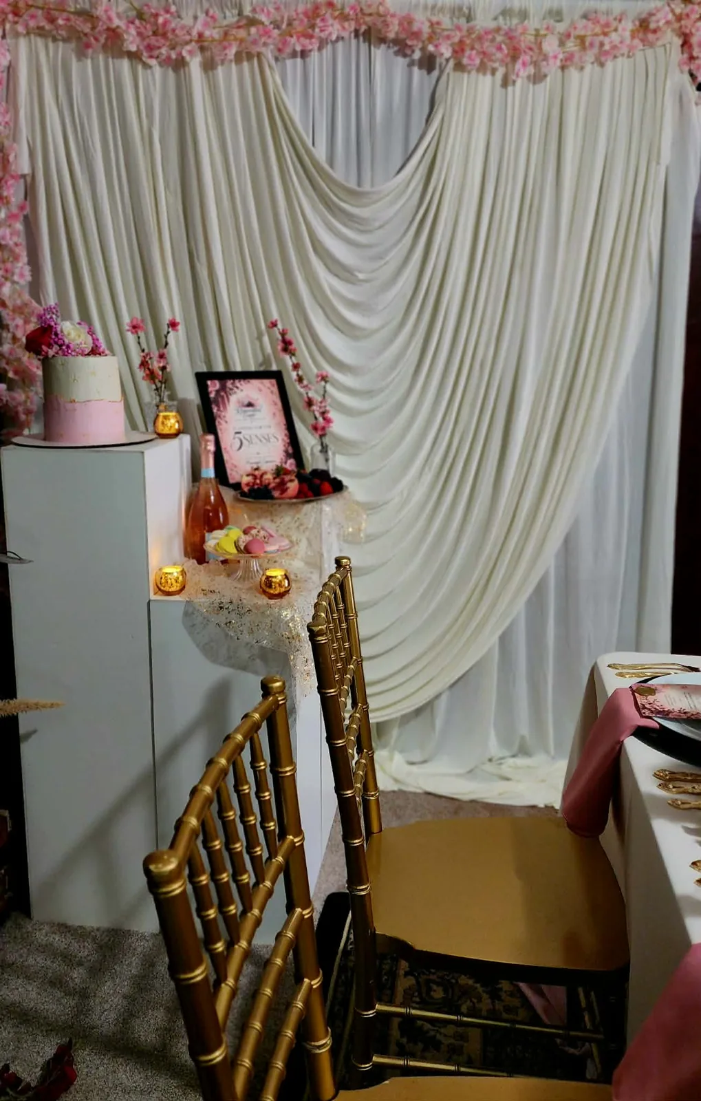 Dessert corner with ivory swag draping, cherry blossom garland, and gold chairs